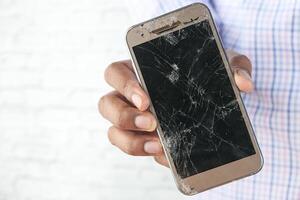 Mens Holding smartphone met een gebroken scherm. foto