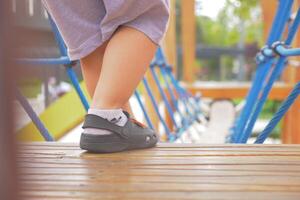 een weinig meisje in roze schoenen is staand Aan een houten dek foto