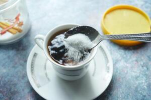 gieten wit suiker in een koffie kop , foto