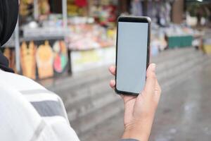 Holding slim telefoon met leeg scherm met wazig cafe straat achtergrond. foto