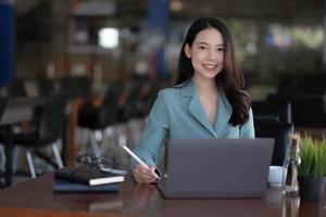 charmante Aziatische zakenvrouw zitten werken op laptop in kantoor. foto