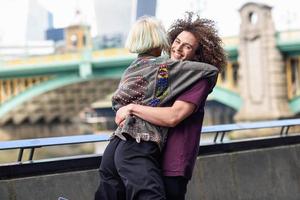 gelukkig paar knuffelen in de buurt van de Southwark-brug over de rivier de Theems, Londen foto