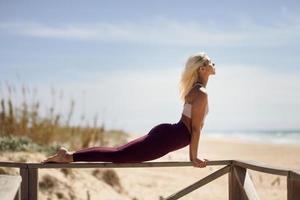 Kaukasische blonde vrouw die yoga beoefent op het strand foto