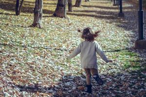 klein meisje speelt in een stadspark in de herfst foto