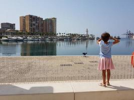 klein meisje kijkt naar de haven van Malaga foto