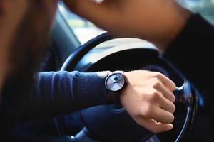 jonge man die op zijn horloge in de auto kijkt tijdens de verkeersopstopping, close-up foto
