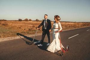 lachend bruidspaar rijden op scooters langs de weg foto