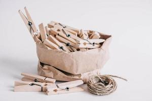 houten wasknijpers in papieren zak met touw op witte achtergrond
