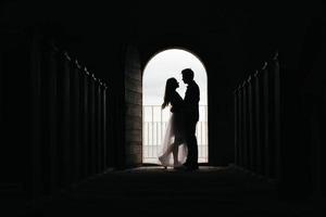silhouet van verliefde paar knuffelen terwijl staande in de deuropening op zwarte achtergrond foto