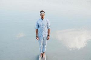man staat op houten brug en kijkt naar de waterreflex van blauwe lucht foto