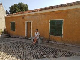 foto van een vrouw zittend buiten een oude huis in Sardinië laatste zomer.