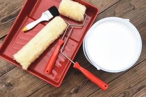 geschilderd gereedschap met roller kwast verfemmer ingeblikte verf voor het schilderen op houten ondergrond, bovenaanzicht op verfbak foto