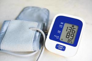 bloeddrukmeter digitaal op tafel, medische elektronische tonometer controleer bloeddruk en hartslag gezondheid en medisch concept. foto