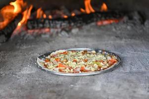 pizza gebakken in de oven - zelfgemaakte pizza pizza italiaans wordt gekookt in een houtgestookte oven koken in een traditioneel gerecht foto