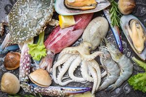 verse rauwe zeevruchten buffet met citroen rozemarijn ingrediënten kruiden en specerijen - zeevruchten schaaldieren op ijs bevroren met garnalen garnalen krabklauwen shell mossel inktvis octopus en mosselen in het restaurant foto