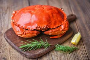 verse krab met ingrediënten citroen rozemarijn op een houten bord - zeevruchten schaaldieren gestoomde rode krab of gekookte steenkrab foto