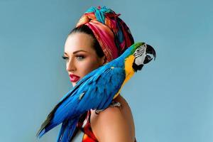 portret van jonge aantrekkelijke vrouw in Afrikaanse stijl met ara papegaai op haar hand op kleurrijke achtergrond