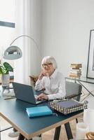 moe senior mooie grijze haren vrouw in witte blouse lezen van documenten op kantoor. werk, senioren, problemen, een oplossing vinden, ervaringsconcept