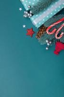 kerst plat lag achtergrond met geschenken, bessen en dennen op turquoise achtergrond verticaal formaat kopieerruimte foto