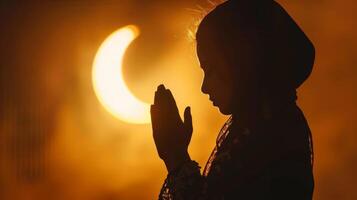 silhouet van jong moslim meisje bidden met handen samen tegen backdrop van halve maan maan, symboliseert Ramadan, Islam, en spiritualiteit. foto