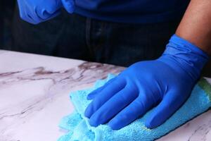 hand in blauwe rubberen handschoenen met spuitfles foto