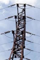 hoogspanning elektrische toren. hoogspanningslijnen en hoogspanningsmasten op een zonnige dag met cirkelvormige wolken in de blauwe lucht. hoogspanningstransmissielijn ondersteunt. ze hebben een complexe staalconstructie. foto