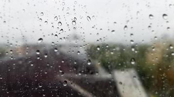 nat raam met druppels op de achtergrond van de herfststad bij bewolkt weer. uitzicht vanuit het raam in de regen. waterdruppel op glazen raam tijdens regen met onscherpe achtergrond van stadsscène foto