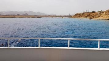 prachtig uitzicht vanaf het dek van een cruiseschip in de rode zee in egypte. egyptisch rotsachtig kustlandschap met een jacht. deel van het schip tegen de achtergrond van de woestijn en de zee. foto