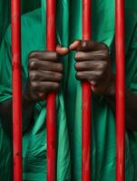handen van een Afrikaanse Mens Holding rood gevangenis bars. eenheid, zwart geschiedenis maand achtergrond. foto