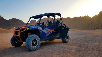 Egypte, Sharm el Sheikh - 07 juni 2019. een blauwe buggy staat in de woestijn te midden van bergen bij zonsondergang zonder mensen foto