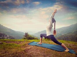 vrouw aan het doen yoga asana virabhadrasana 1 - krijger houding buitenshuis foto