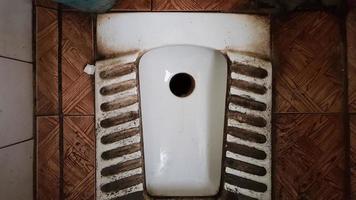 vies oud en stoffig toilet in een openbaar verlaten gebouw. verwoeste hygiëne kamer. foto