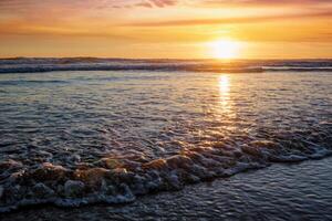 atlantic oceaan zonsondergang met stijgende golven Bij fonte da telha strand, Portugal foto