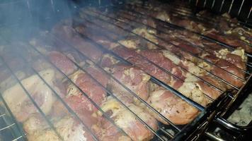 het proces van het koken van shish kebab op de grill. sappig en geurig vlees kwijnt weg van vuur en rook. platteland picknick concept 's nachts. smakelijk en voedzaam picknickgerecht in de open lucht.