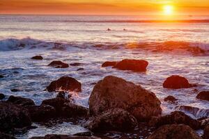 atlantic oceaan zonsondergang met golven en rotsen Bij costa da caparica, Portugal foto