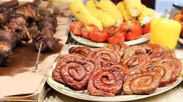 een toonbank met bakjes met gegrilde worstjes en vlees. ronde barbecue worst street food showcase. vers gegrilde ronde worstjes op een straatvoedselfestival. een verscheidenheid aan vleesdelicatessen foto