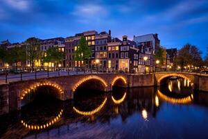 Amsterdam kanaal, brug en middeleeuws huizen in de avond foto