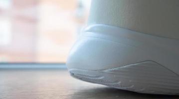 lage hoekmening van de buitenzool van de achterkant van nieuwe witte sneakers. rubberen zool op de hiel van herenschoenen. zool voor sport- en wandelschoenen. materiële textuur van sportschoenen. foto