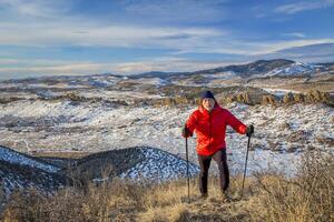 senior mannetje wandelaar bereiken top van een heuvel Bij uitlopers van rotsachtig bergen - winter landschap Bij duivel ruggegraat Open ruimte in de buurt liefdesland, Colorado foto