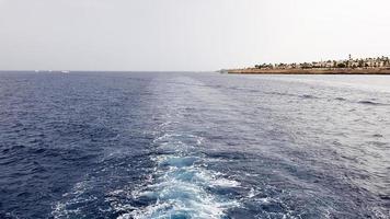 cruiseschip of parcours op het oppervlak van de blauwe rode zee. zeewaterschippad met witte schuimige golf. bovenaanzicht van de diepe oceaan. perspectief van een golf van wit water. foto