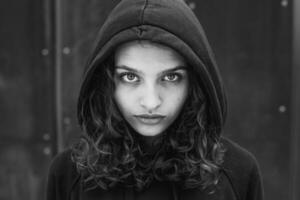 wit brunette tiener- meisje met gekruld haar- poses Aan de straat in de stad. foto