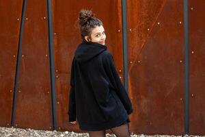 wit brunette tiener- meisje met gekruld haar- poses Aan de straat in de stad. foto