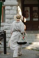 een vrouw in een hoed in een wit kleding met een zak wandelingen in de omgeving van de livadia paleis foto