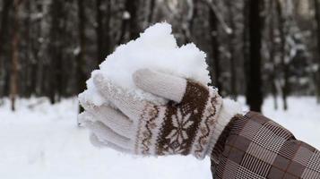 vrouwenhanden in gebreide wanten houden natuurlijke zachte witte sneeuw buiten op een winterdag. vrolijke wintertijd. hand houdt koude sneeuw vast. tijd doorbrengen in de natuur in de winter. foto