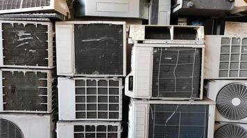 een groep vuile, stoffige en kapotte airconditioningcompressoren wordt op een stortplaats gestapeld. veel oude airconditioners en op straat bij de reparatiewerkplaats. foto