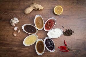 sauzen en specerijen. een reeks van populair sauzen en specerijen Aan een houten achtergrond. foto