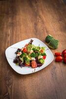 groente salade met Mozzarella, tomaten, broccoli en basilicum in een bord Aan een houten achtergrond top visie. foto