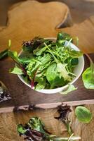 vegetarisch salade van een mengen van vers bladeren in een bord Aan een houten achtergrond foto