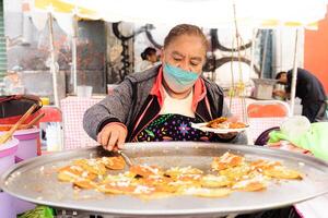 puebla, Mexico 2023 - senior dame bereidt zich voor chalupa's poblana's ondergedompeld in vet, Mexicaans voedsel van de stad van puebla, Mexico foto