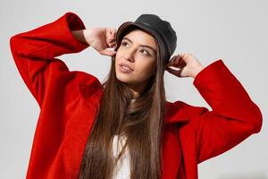 modieus winter accessoires. mooi meisje in zwart hoed en rood jas verheven handen en Holding pet in studio Aan wit achtergrond. foto